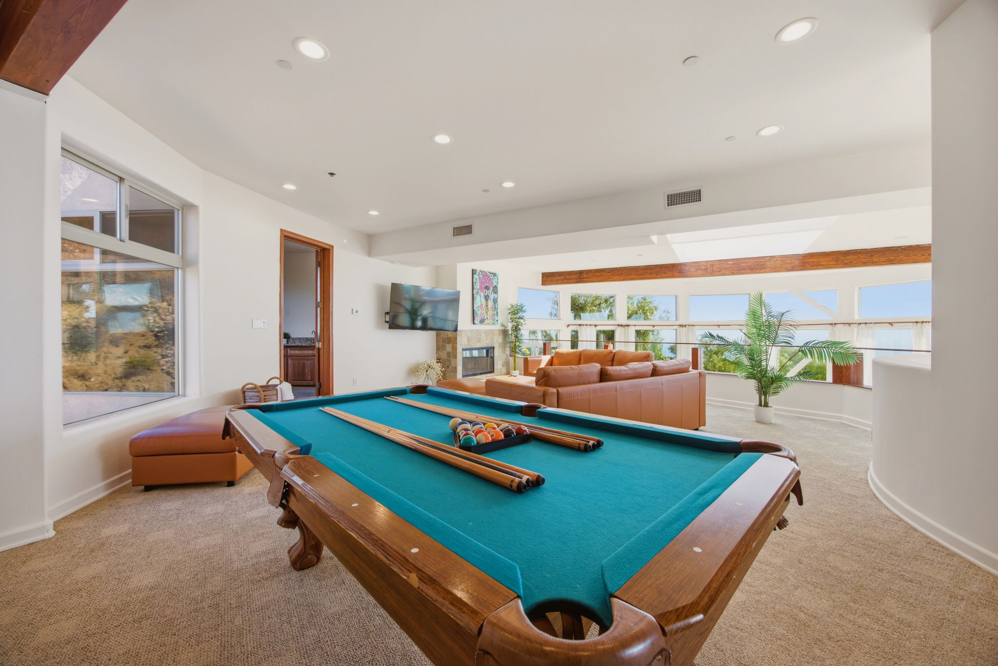 Upstairs lounge with billiards table, fireplace, and wraparound ocean-view windows