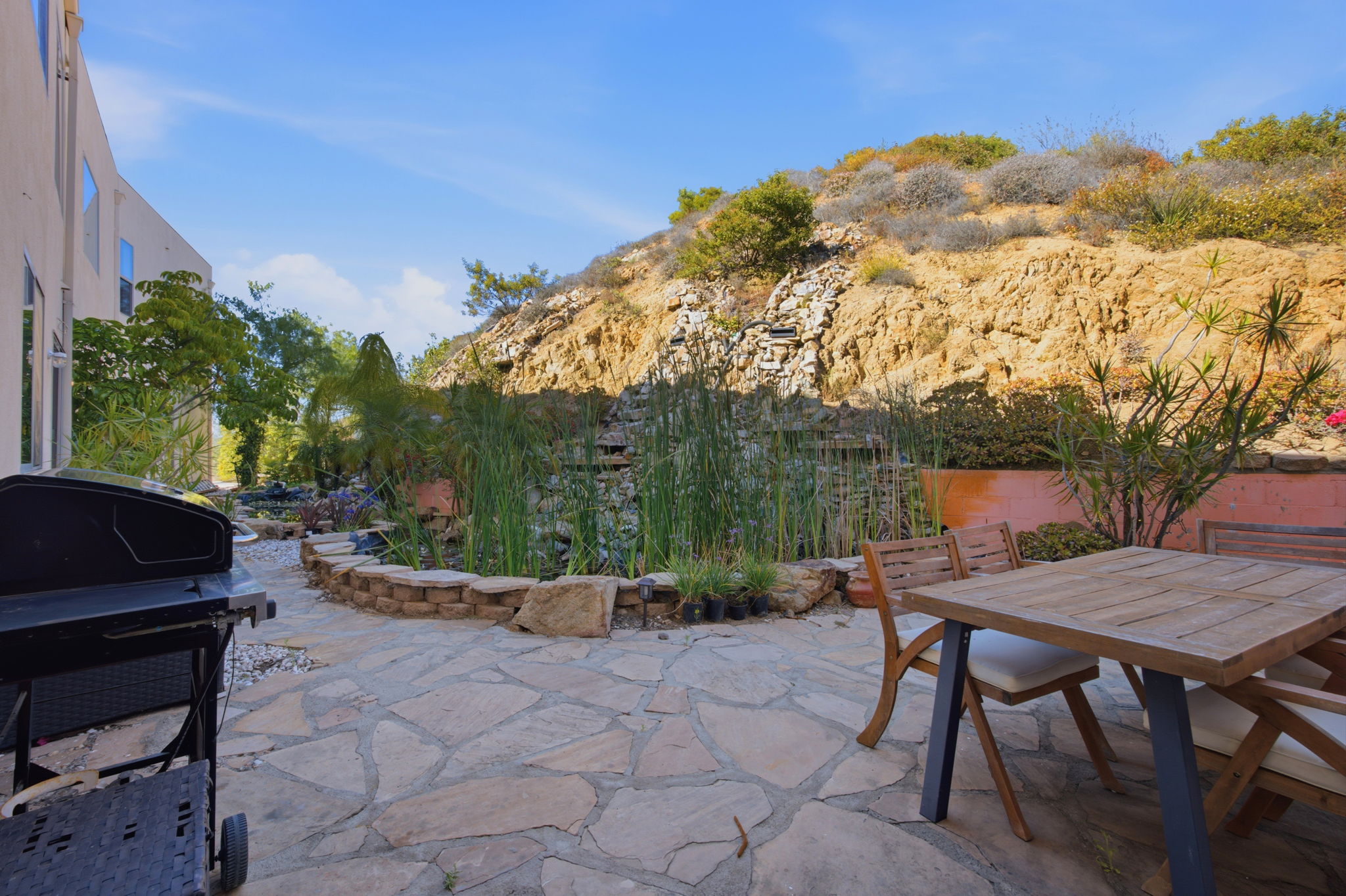 Flagstone patio and rock waterfall pond tucked against the protected hillside