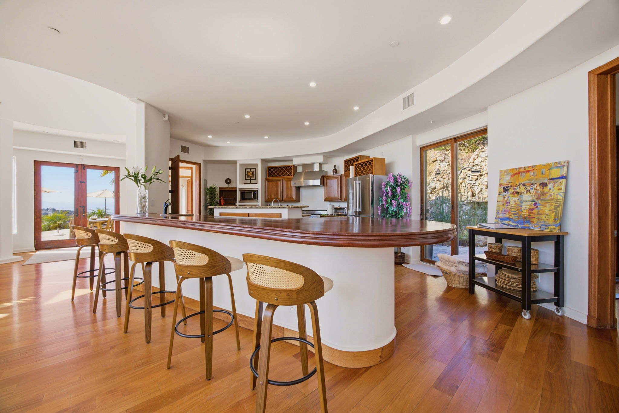 Curved mahogany breakfast bar seating five, open to the kitchen