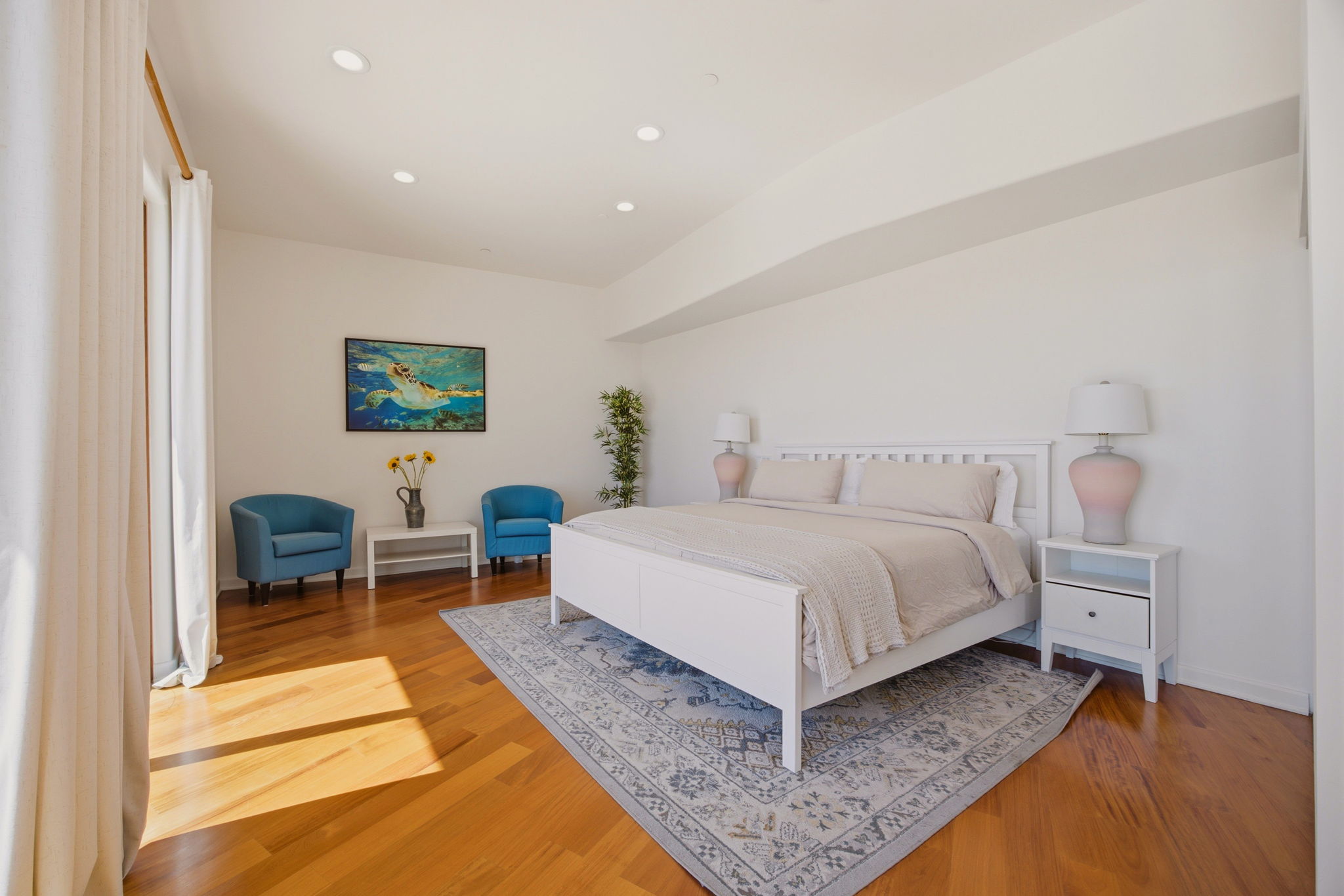 Sunlit bedroom with rich mahogany floors and sheer curtains at the terrace doors